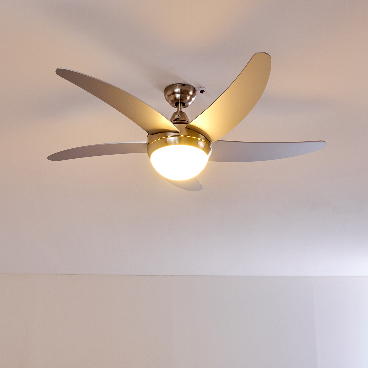 Ein moderner Deckenventilator mit fünf silbernen Flügeln und integrierter Beleuchtung.