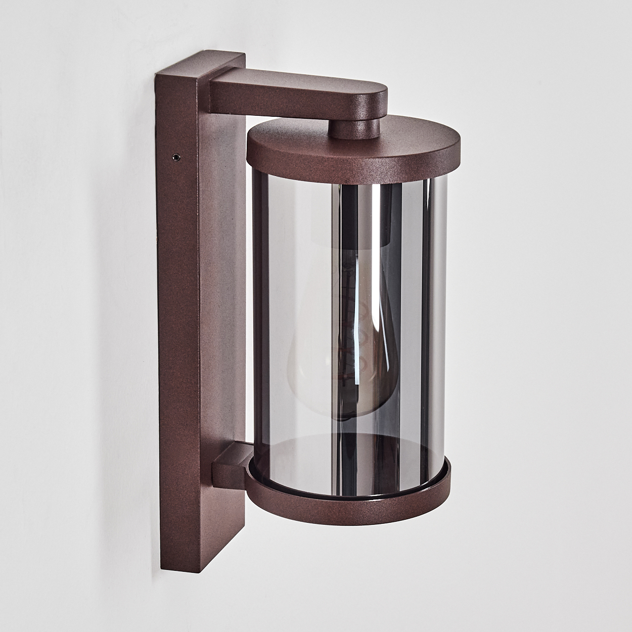 Eine braune Wandleuchte mit Glaszylinder und sichtbarer Glühbirne.