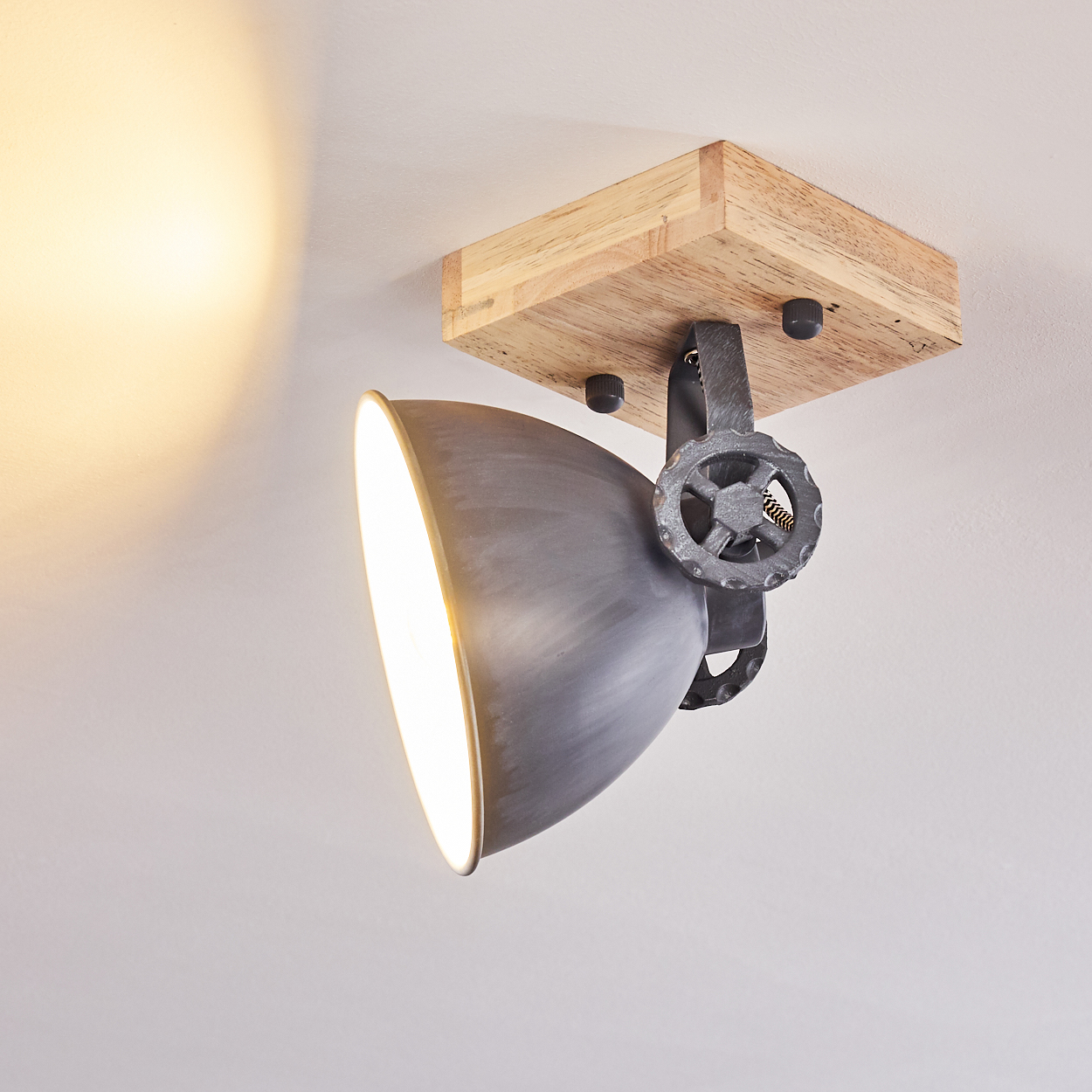 Grauer Lampenschirm mit Holzbasis und Einstellrad an einer weißen Decke.