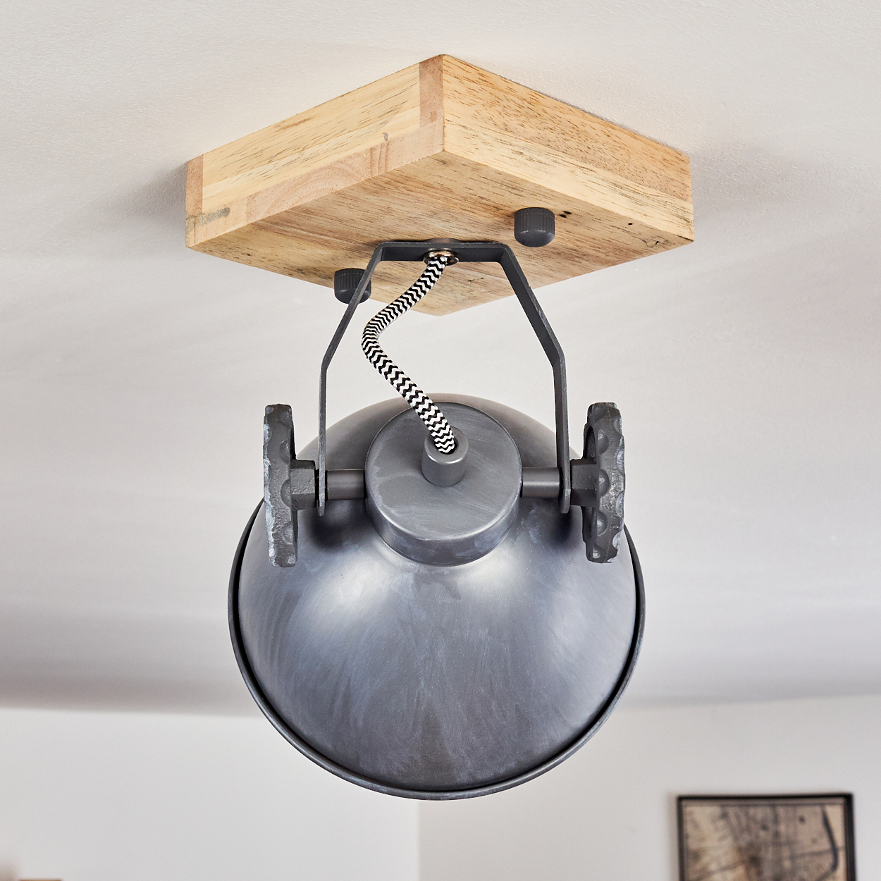 Eine graue Pendelleuchte mit Holzdecke und schwarz-weißem Kabel.