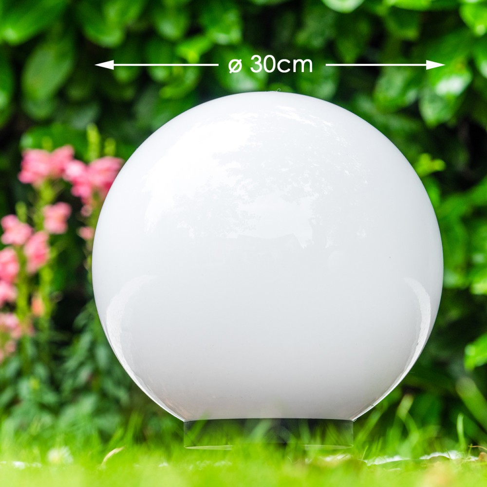 Eine weiße Kugel mit 30cm Durchmesser steht im Gras, hinter ihr grünes Laub.