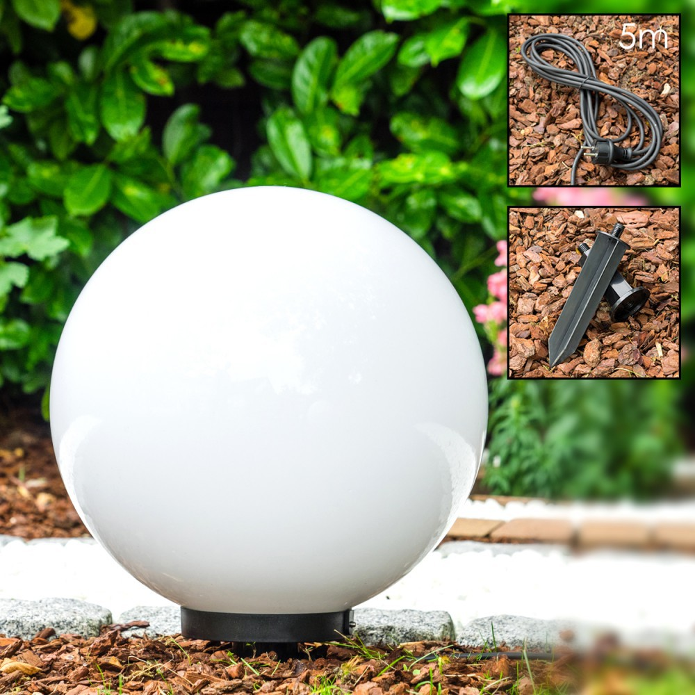 Eine weiße Kugelleuchte steht im Garten mit grünen Büschen dahinter.