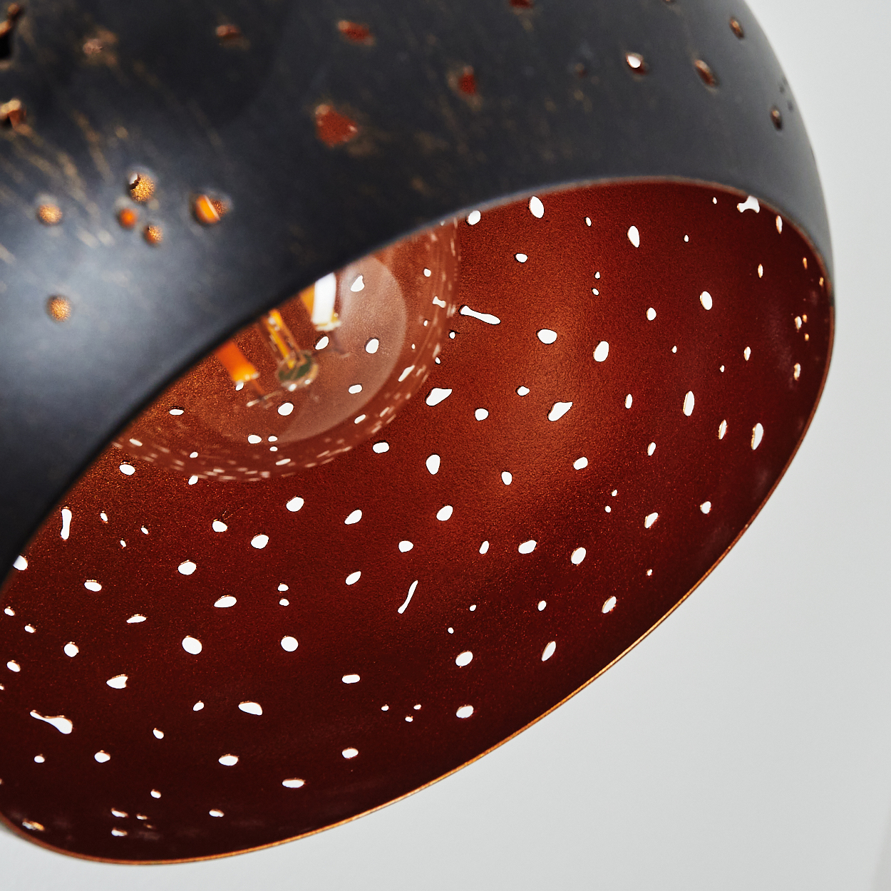 Schwarze Lampe mit kupferfarbener Innenseite und vielen kleinen Löchern.