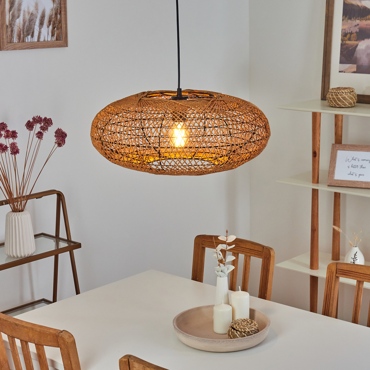 Ovaler Rattan-Pendelleuchter über einem Esstisch mit Kerzen und Deko.