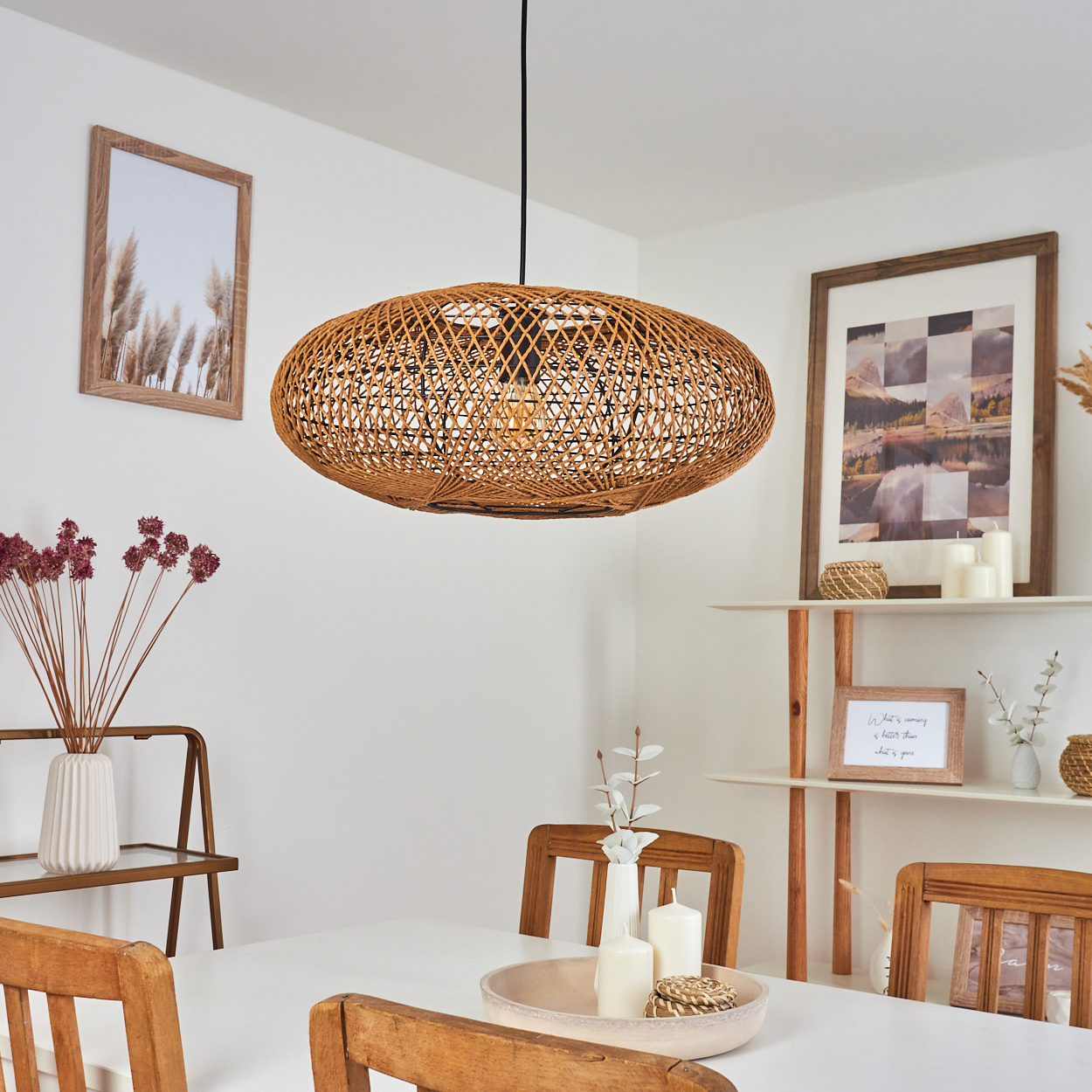 Ein Esstisch mit Holzsesseln unter einer Weidenlampe. Dekoriert mit Vasen und Bildern.
