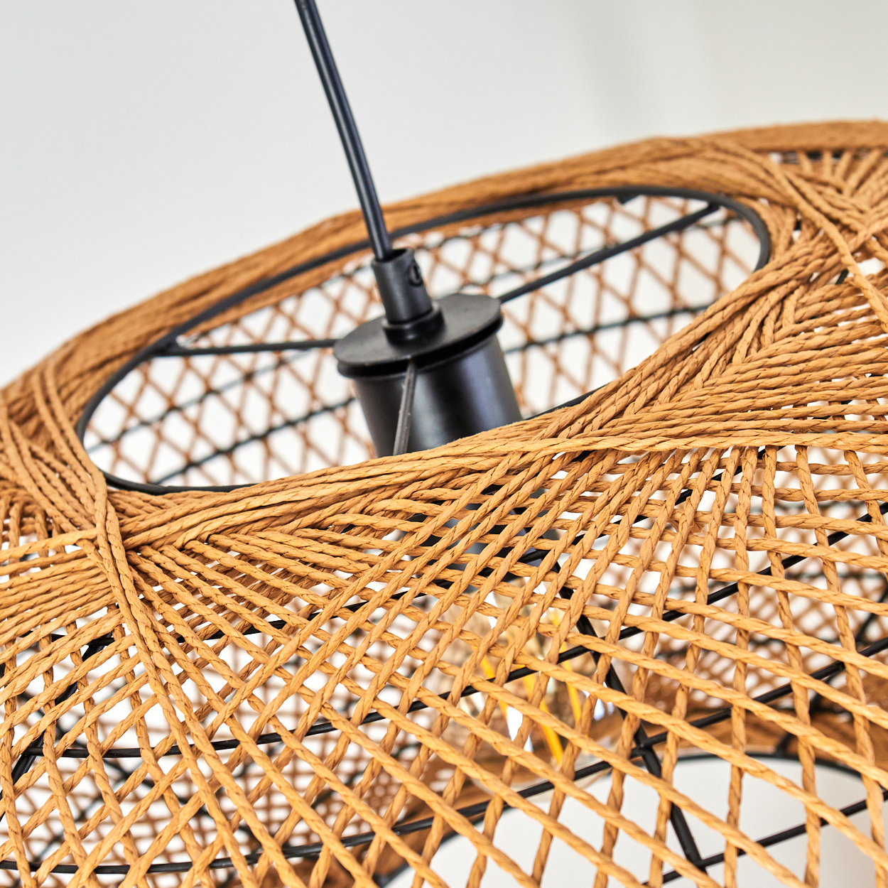 Ein brauner Rattankorb-Lampenschirm mit schwarzem Metallgestell und Kabel.