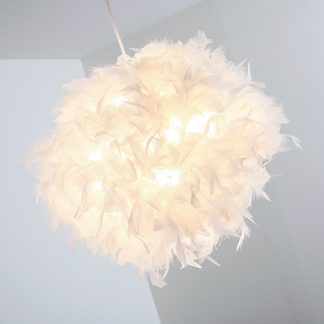 Eine weiße Federlampe hängt von der Decke, beleuchtet von innen.