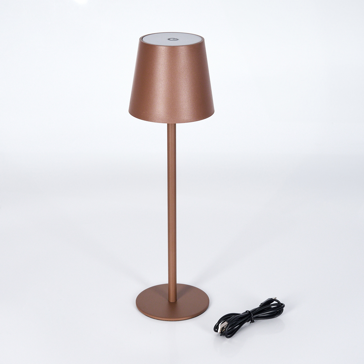 Eine kupferfarbene Tischlampe mit rundem Fuß und Ladekabel.