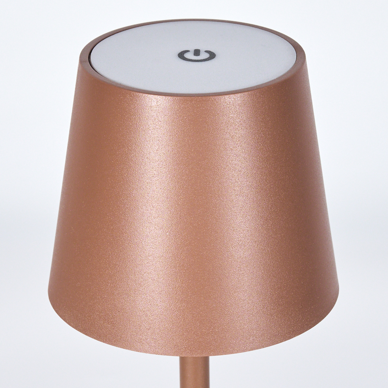 Eine kupferfarbene Lampe mit einem weißen Knopf und einem Ausschaltsymbol.