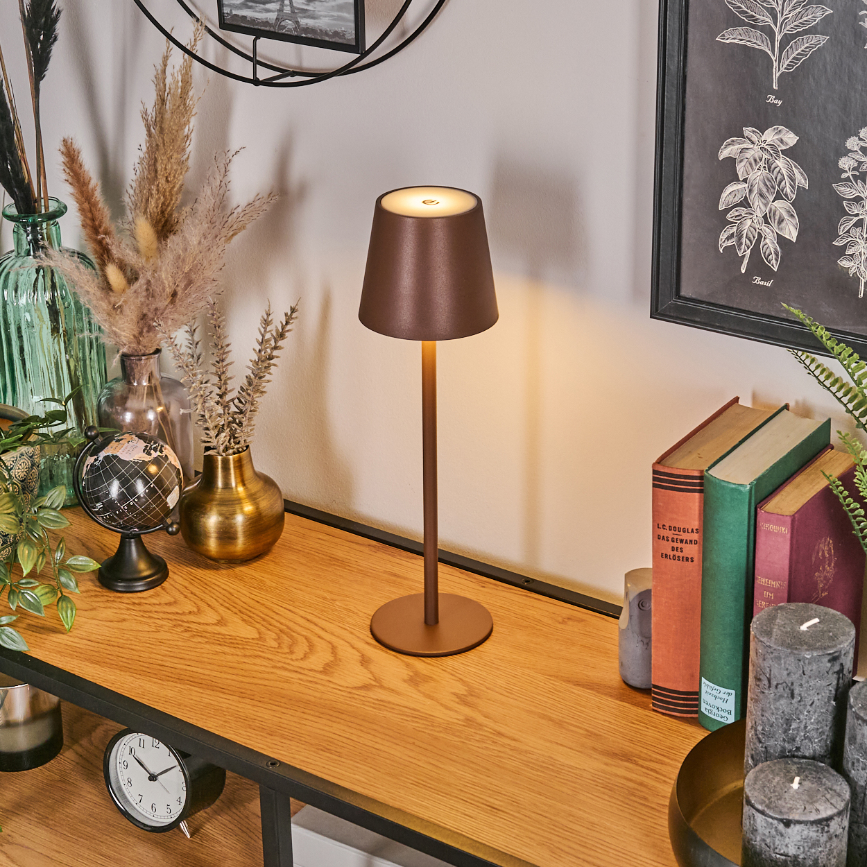 Eine braune Lampe steht auf einem Holzregal neben Büchern und Deko.