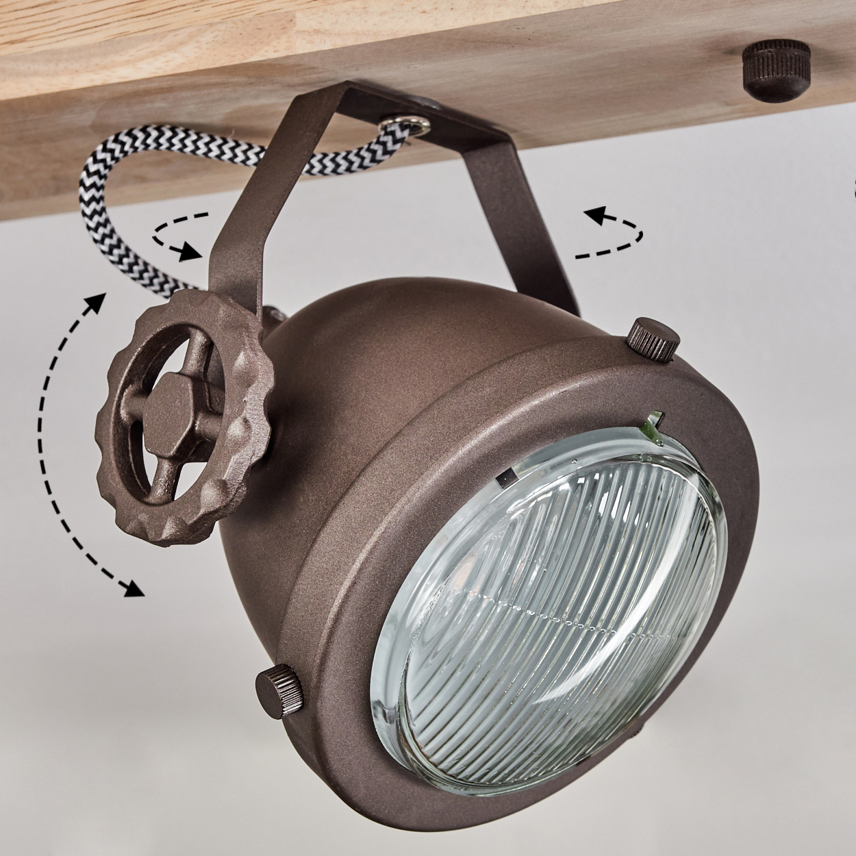 Eine braune Lampe mit Glaslinse hängt an einem Holzbalken. Ein Rad dient zur Verstellung.
