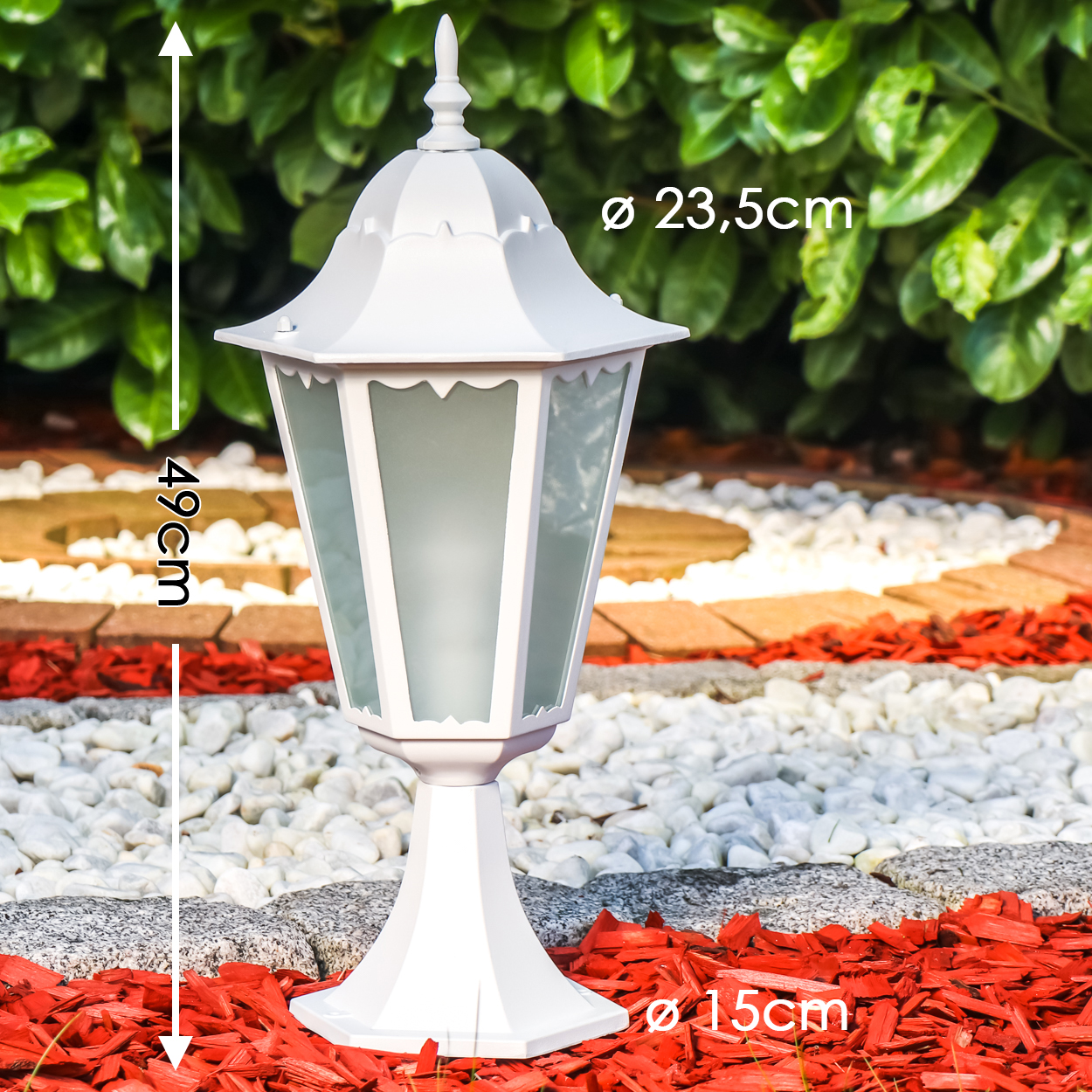 Weiße Laterne mit Glas und Metallgestell auf rotem Mulch und Kies.