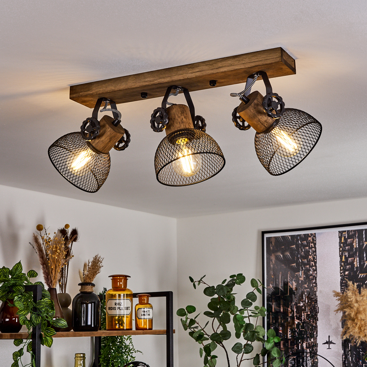 Holz-Deckenleuchte mit drei schwarzen Metallkorb-Schirmen und Edison-Glühbirnen.