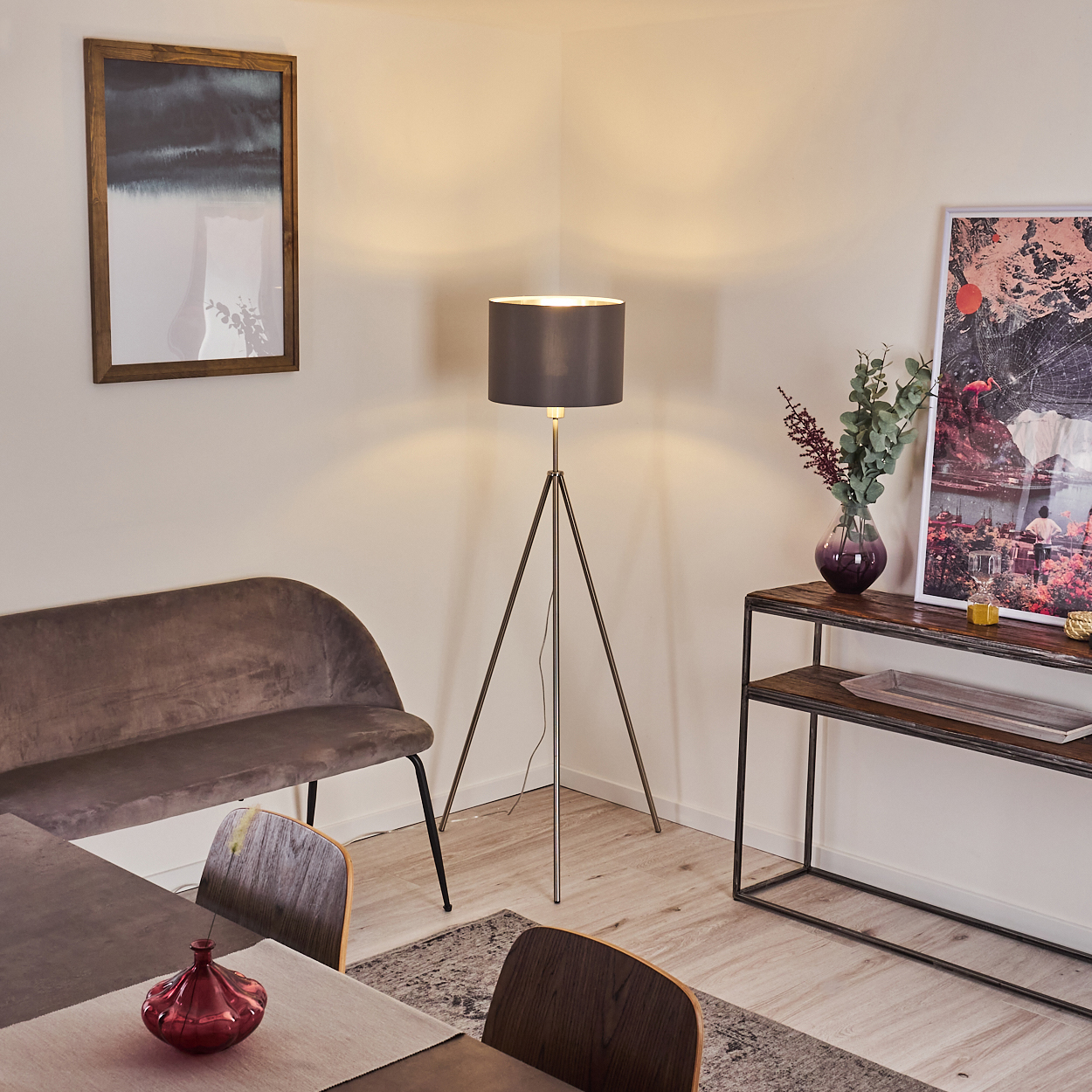 Ein Eckraum mit Sofa, Tisch, Stehlampe und Kunstwerk.