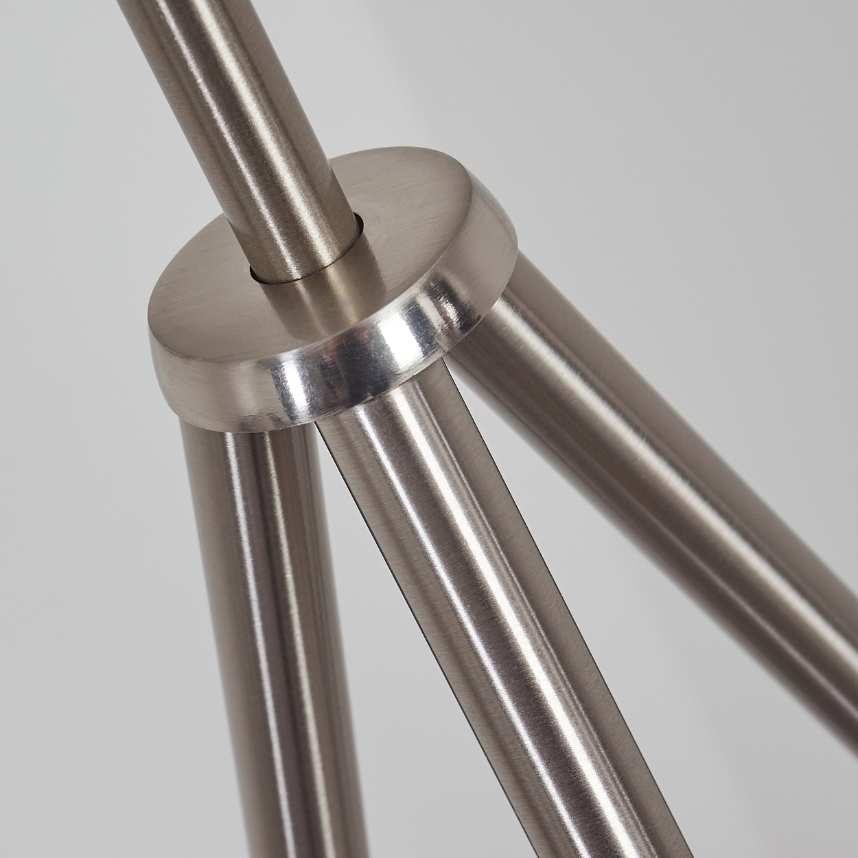 Nahaufnahme einer gebürsteten Metallstruktur mit drei Armen, die sich von einer runden Nabe ausbreiten.