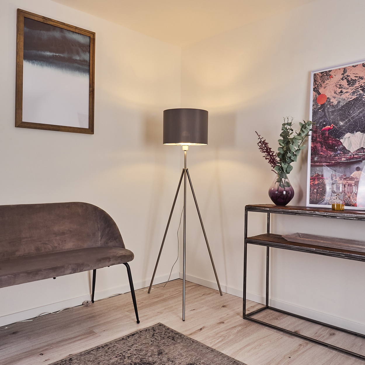 Ein Wohnzimmer mit Sofa, Stativlampe, Konsole und Bildern an der Wand.