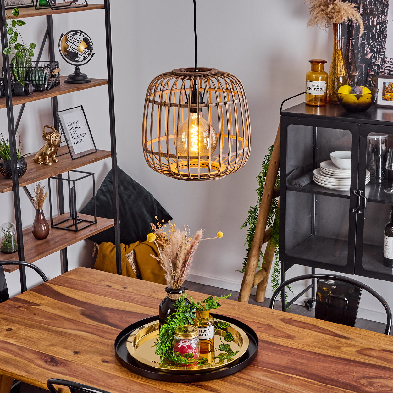 Ein Holztisch mit Tablett, Gläsern & Trockenblumen. Eine Hängeleuchte hängt darüber.