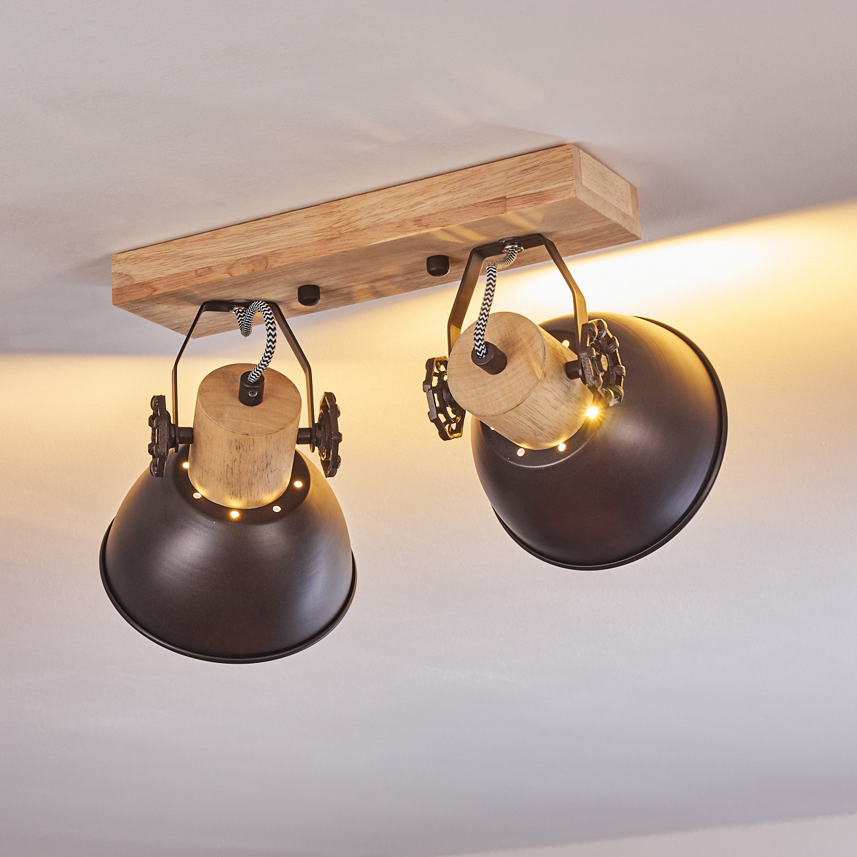 Zwei dunkle Lampen mit Holzakzenten hängen an einem Holzbrett.