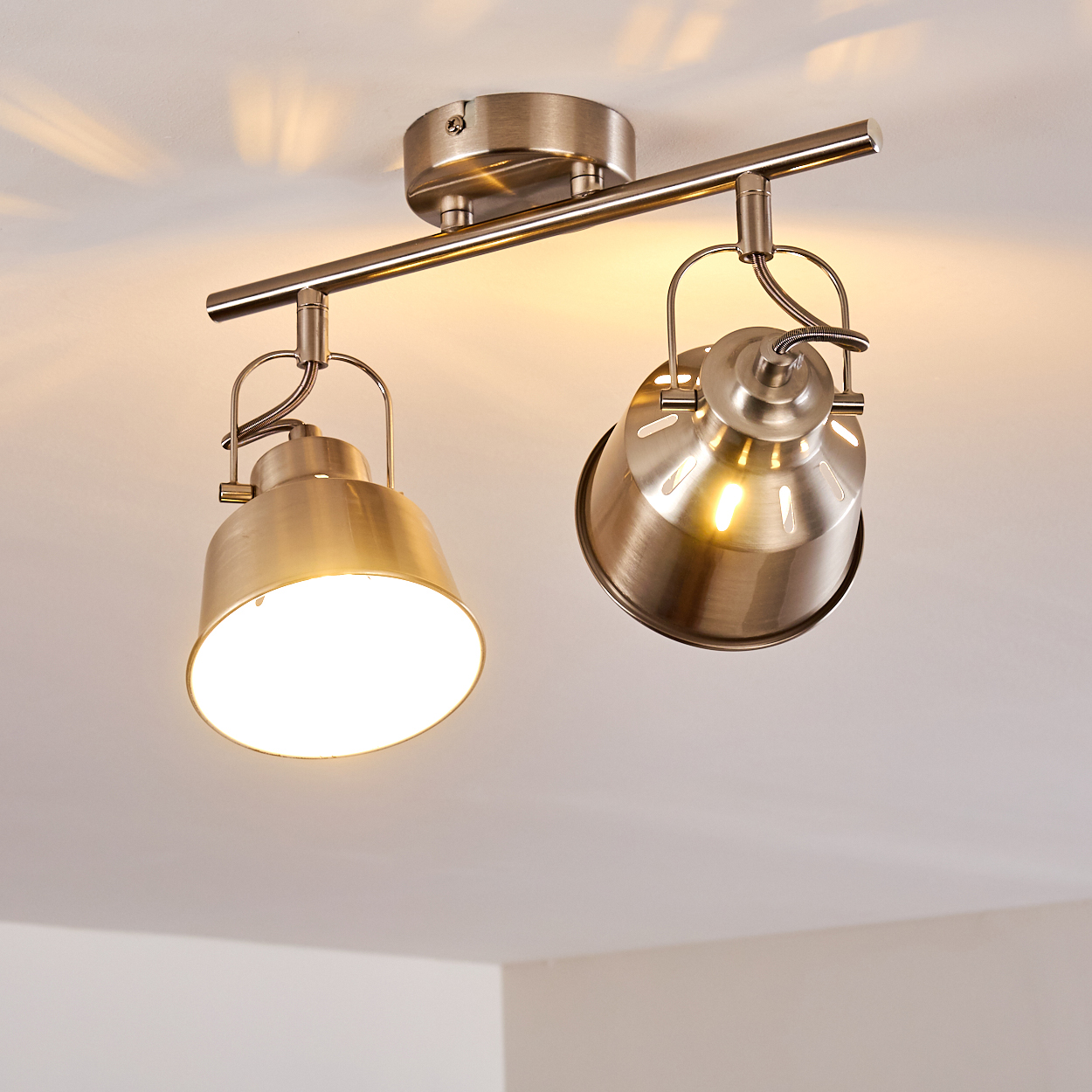 Zwei gerichtete Lampen aus Metall an einer Deckenstange mit weißer Decke.