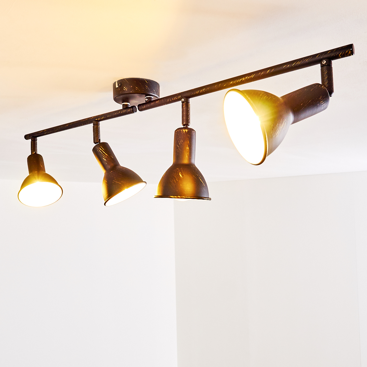 Eine schwarze Deckenleuchte mit vier verstellbaren Spots auf einer weißen Decke.