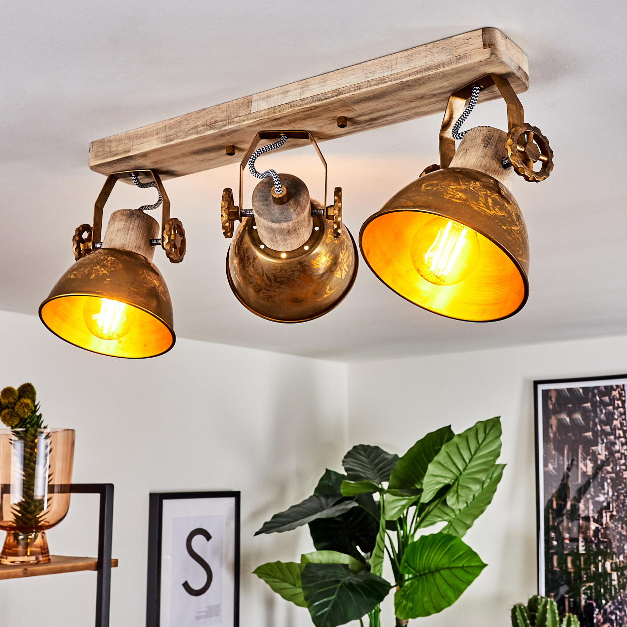 Deckenleuchte mit drei Lampenschirmen aus Messing, Holz und Draht an Holzbalken.