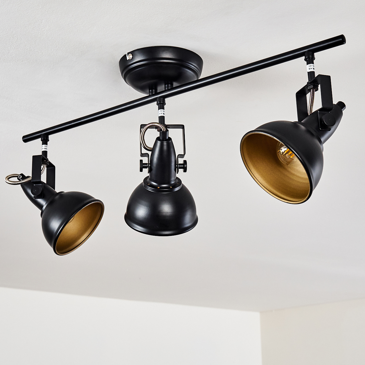 Schwarze Deckenleuchte mit drei verstellbaren Spots mit goldener Innenseite.