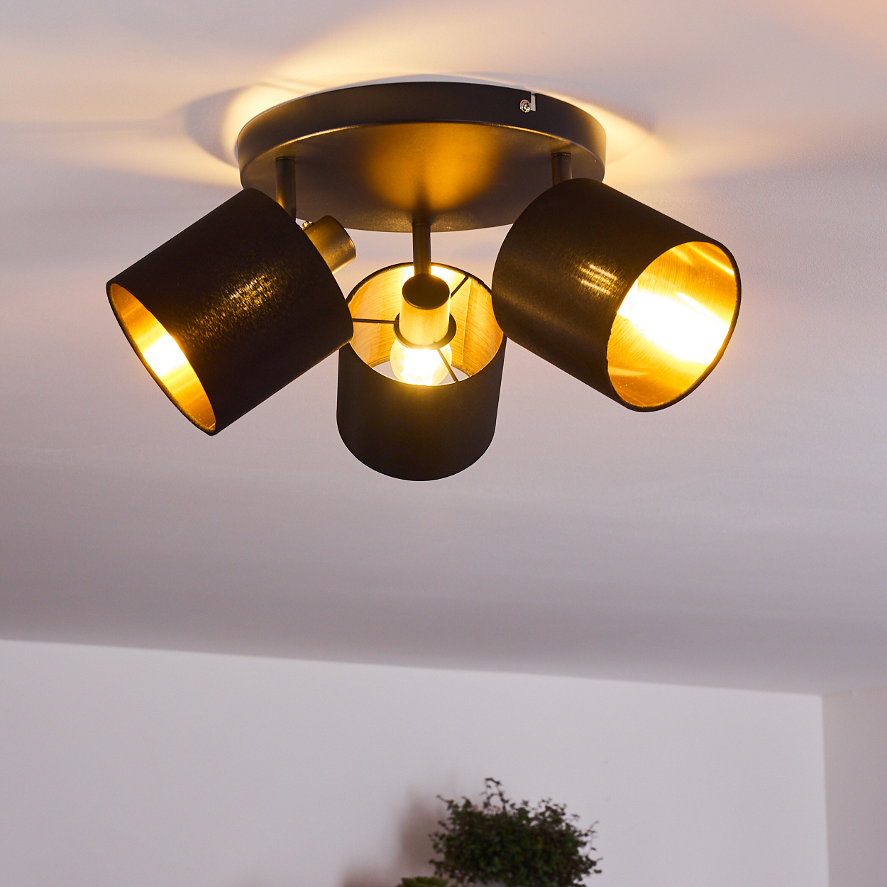 Schwarzer Deckenstrahler mit drei gerichteten Lampenschirmen und goldenen Innenseiten.