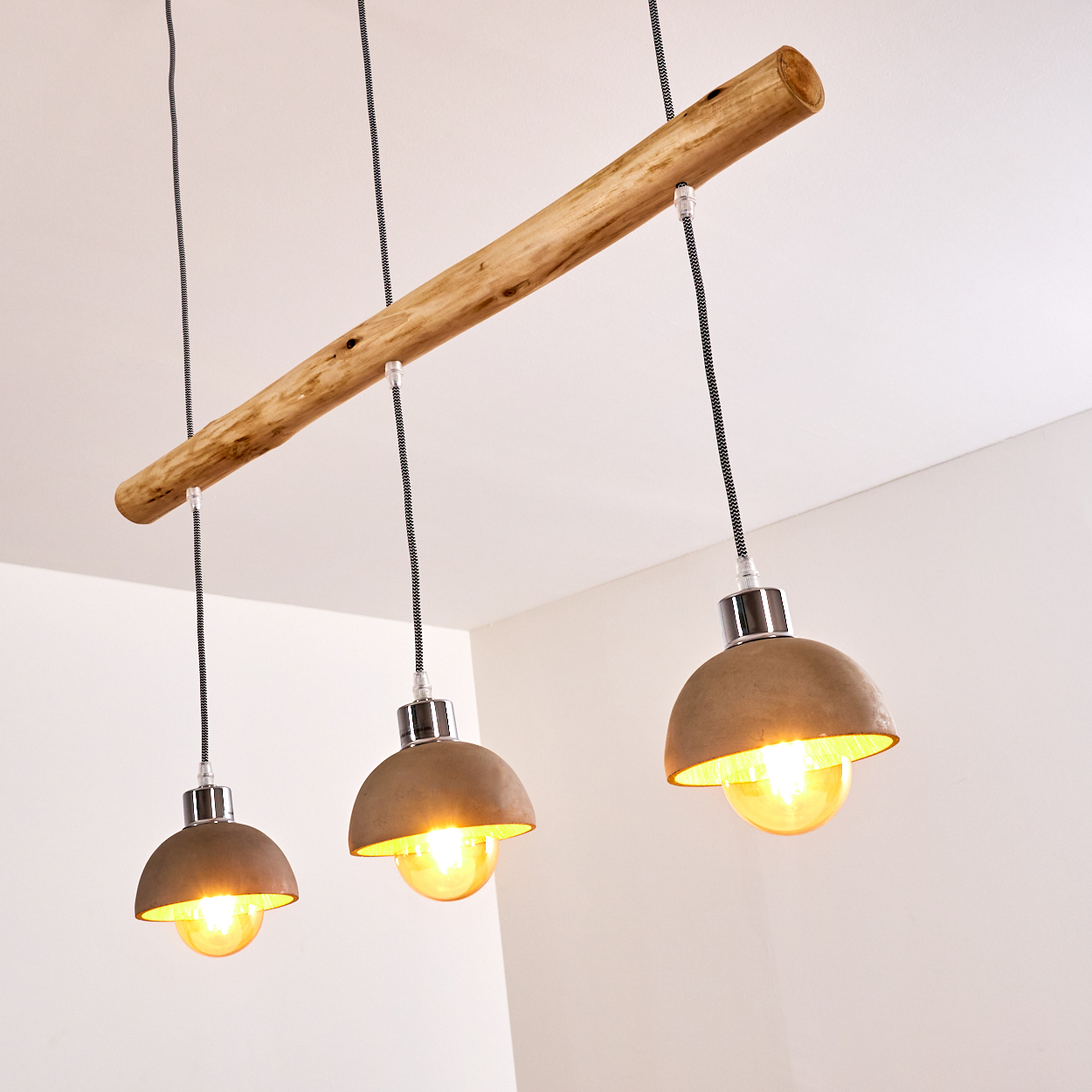 Hängeleuchte mit Holzstamm und drei Betonlampenschirmen mit Glühbirnen.