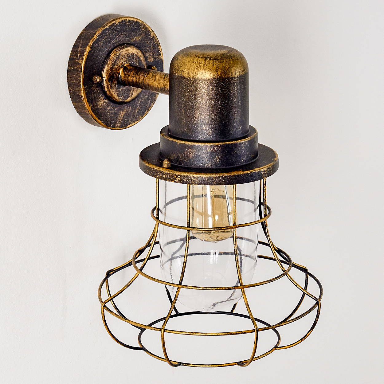 Antike Wandleuchte mit goldener und dunkler Metalloberfläche und Glaskolben.