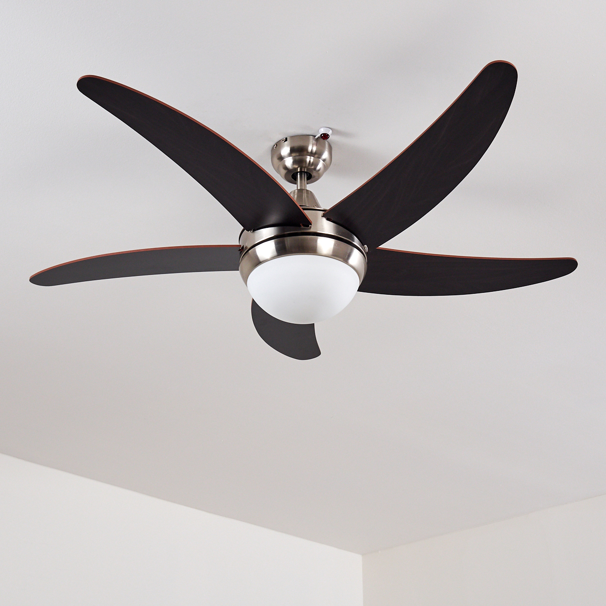 Deckenventilator mit fünf dunklen Rotorblättern und einer runden weißen Leuchte.