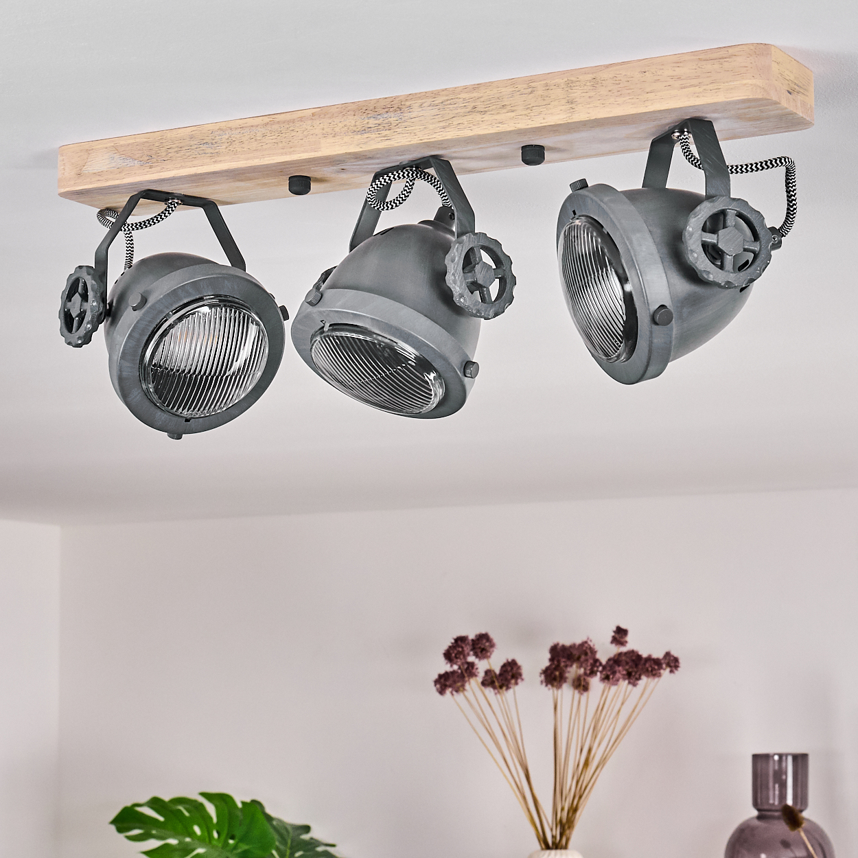 Drei graue Strahler hängen an einem Holzbrett an der Decke.