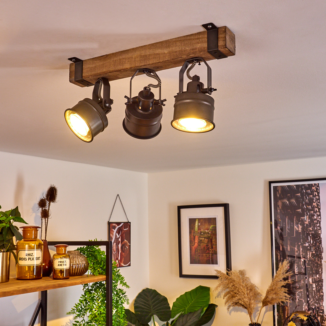 Deckenlampe mit Holzbalken, drei dunklen Spots und Kabelaufhängung.