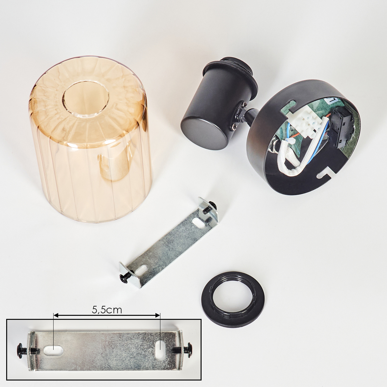 Teile einer Leuchte: Bernsteinfarbener Glaszylinder, schwarze Fassung, Metallhalterung.