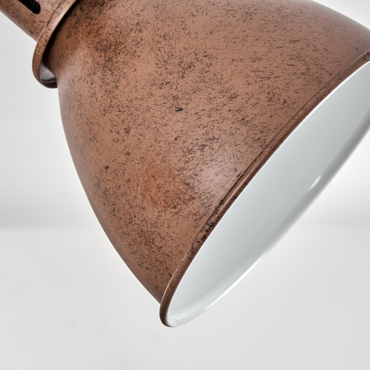 Eine kupferfarbene Lampe mit weißer Innenseite, detailreich und texturiert.