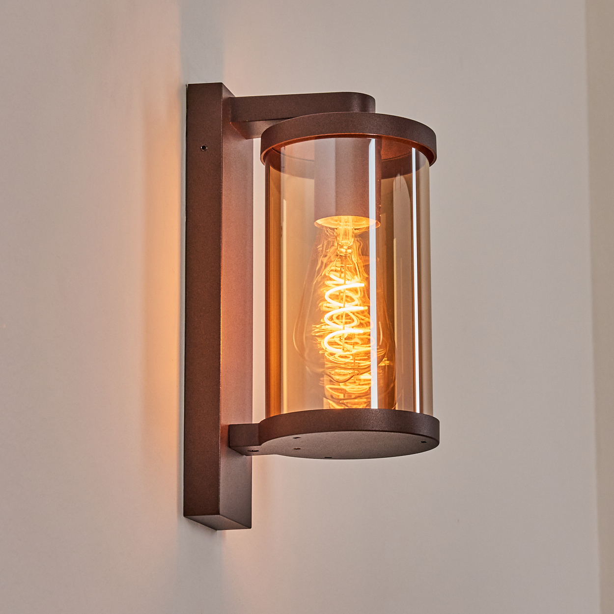 Moderne Wandleuchte mit braunem Metallrahmen und zylindrischem bernsteinfarbenem Glas.