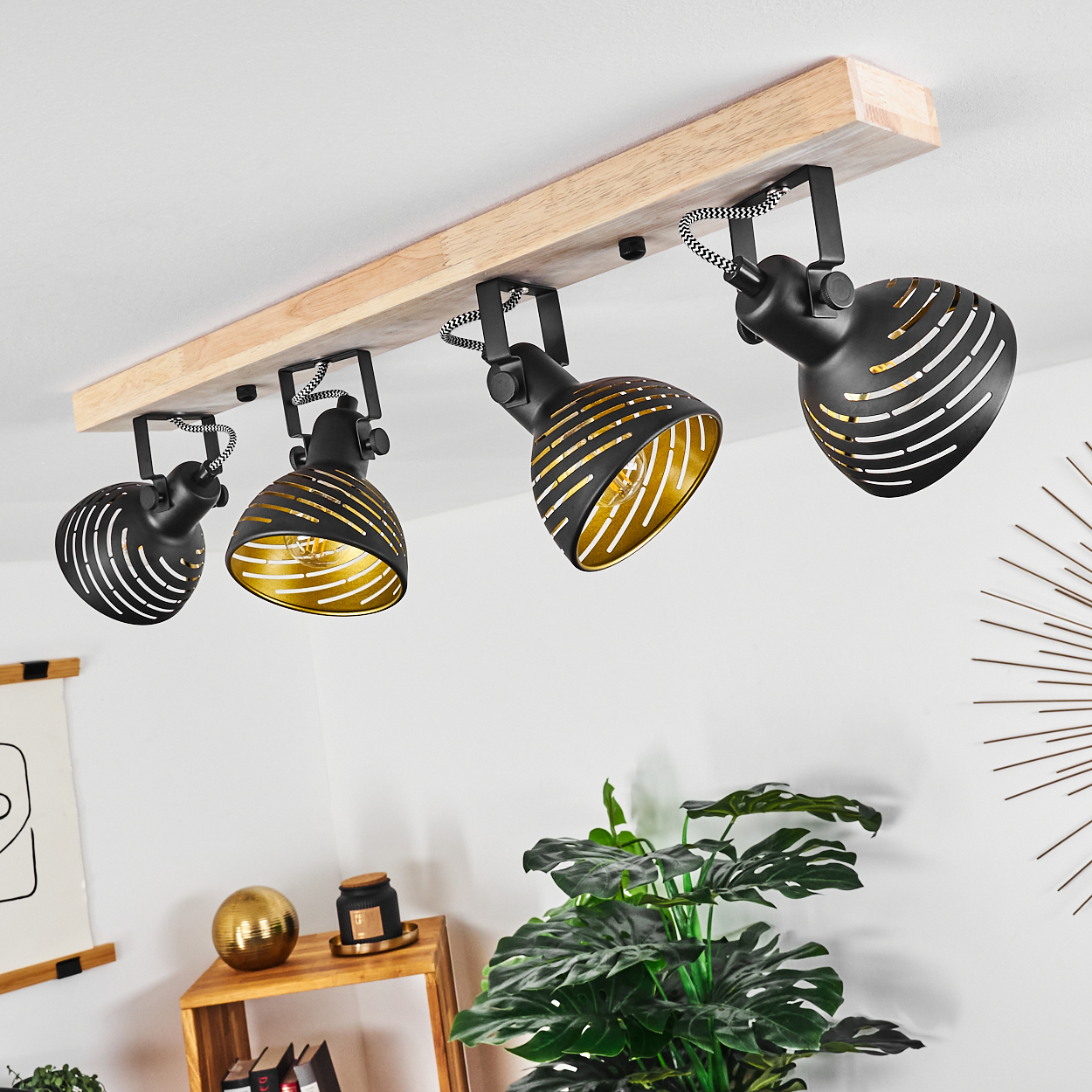 Holzdeckenleuchte mit vier schwarzen Lampenschirmen mit goldenen Innenseiten.