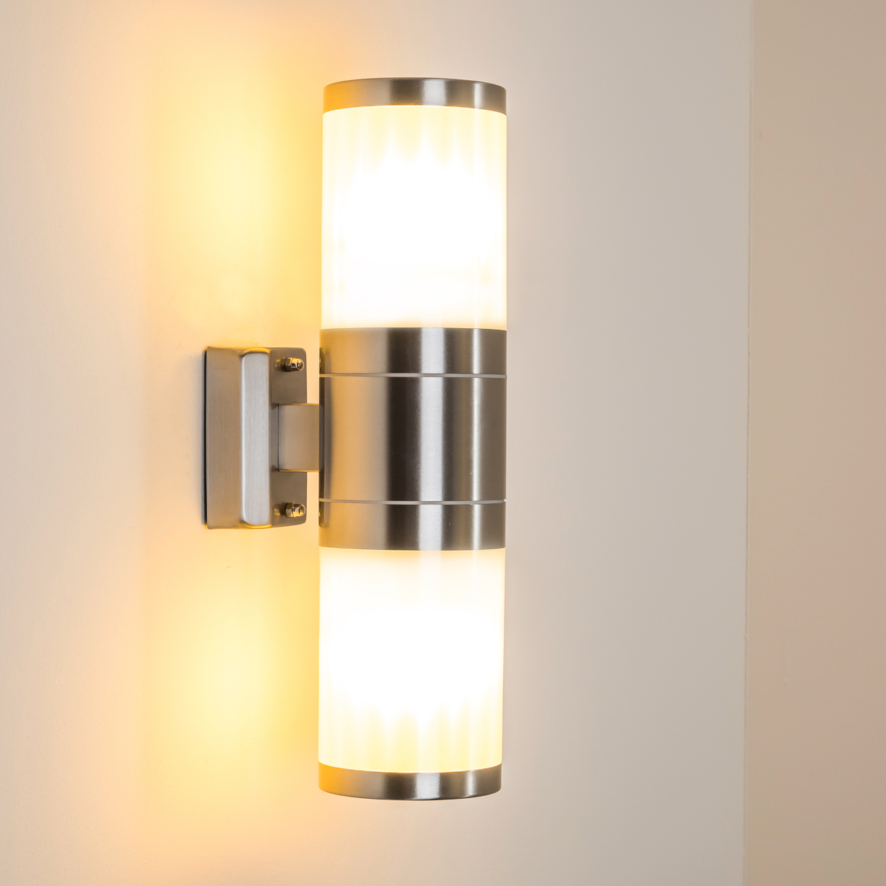 Eine zylindrische Wandleuchte aus Edelstahl mit zwei Lichtern.