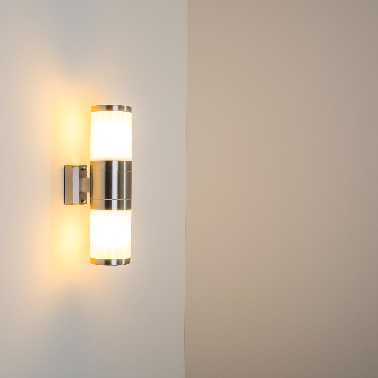 Eine zweiflammige Wandleuchte aus Metall leuchtet nach oben und unten.
