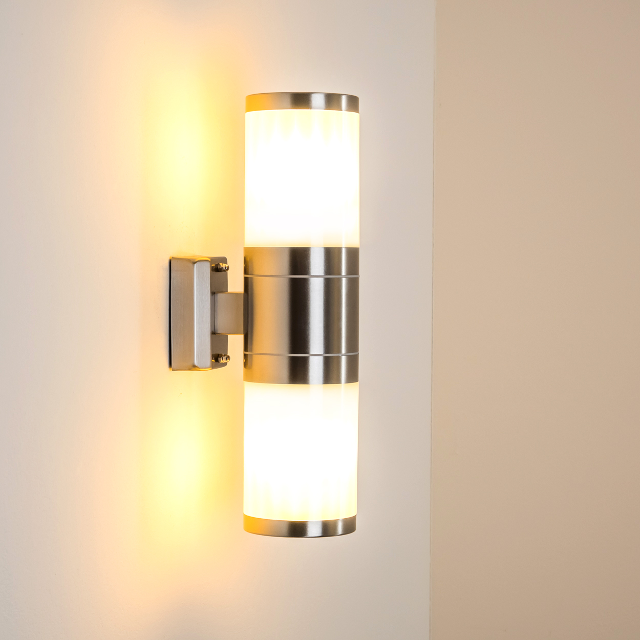 Eine moderne Wandleuchte aus Edelstahl mit zwei zylindrischen Glaskörpern.