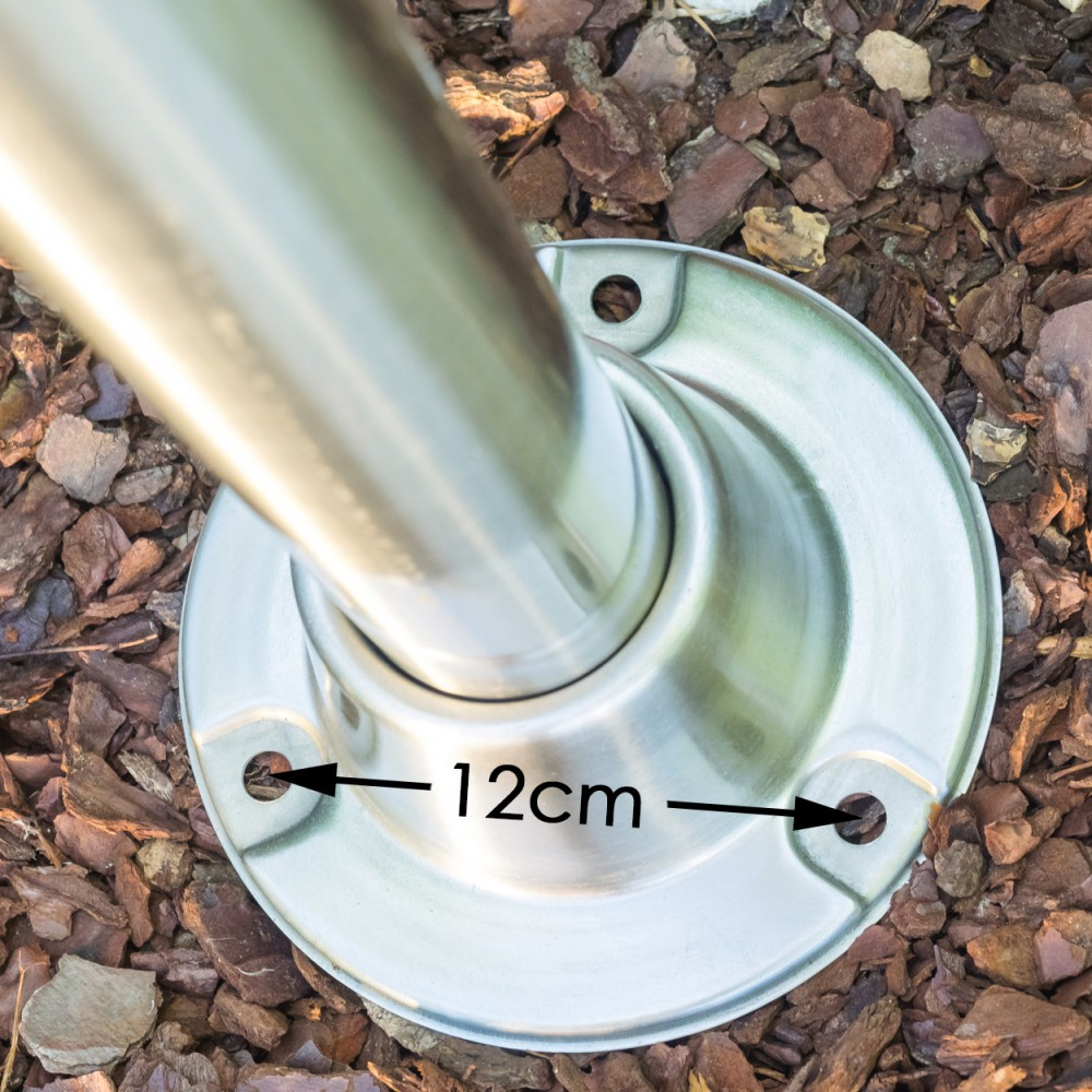 Ein polierter Metallfuß mit drei Schraubenlöchern auf Rindenmulch.