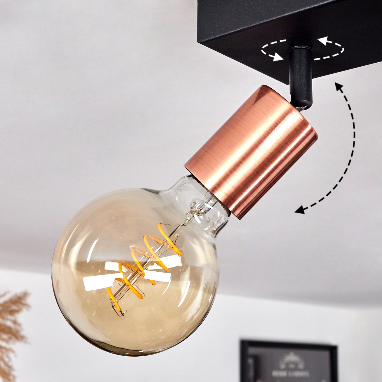 Eine kupferfarbene Lampe mit einem runden Glühbirnenkopf und einem verstellbaren Schwenkarm.