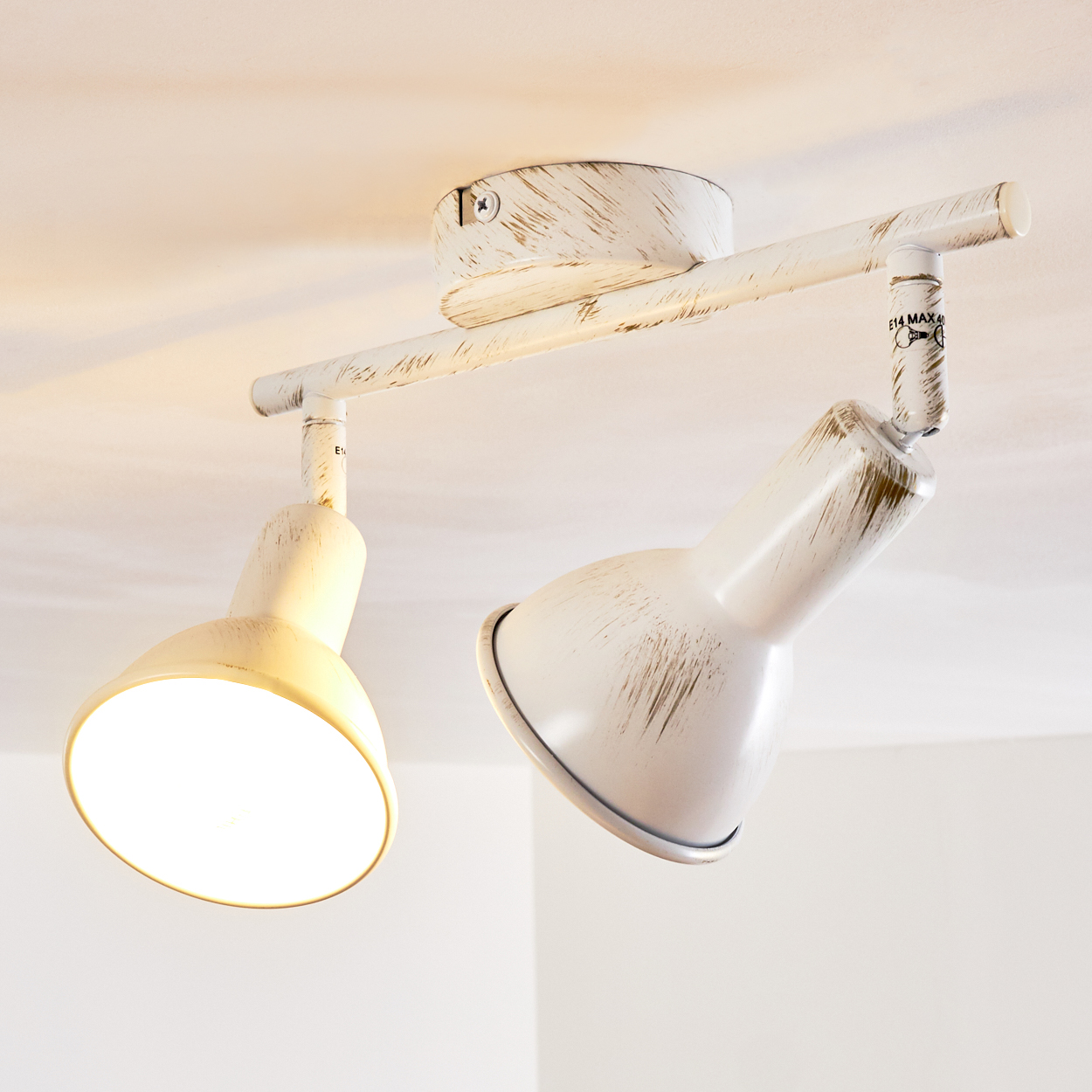Eine weiße Deckenlampe mit zwei verstellbaren Strahlern, eine davon leuchtet.