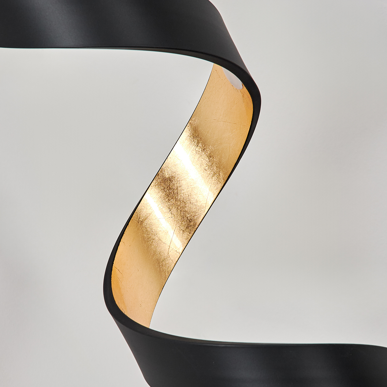 Eine schwarze, geschwungene Form mit einem goldenen Streifen.
