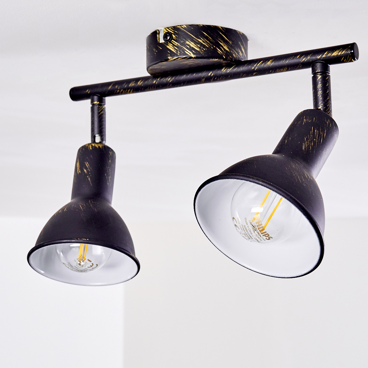 Zwei schwarze Lampen mit goldener Patina an einer Deckenleuchte.