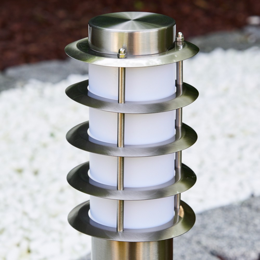 Eine moderne Edelstahl-Gartenleuchte mit weißen Zylindern und Metallringen.