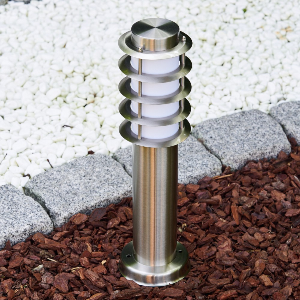 Ein moderner Edelstahl-Gartenlichtpfosten steht auf Rindenmulch.