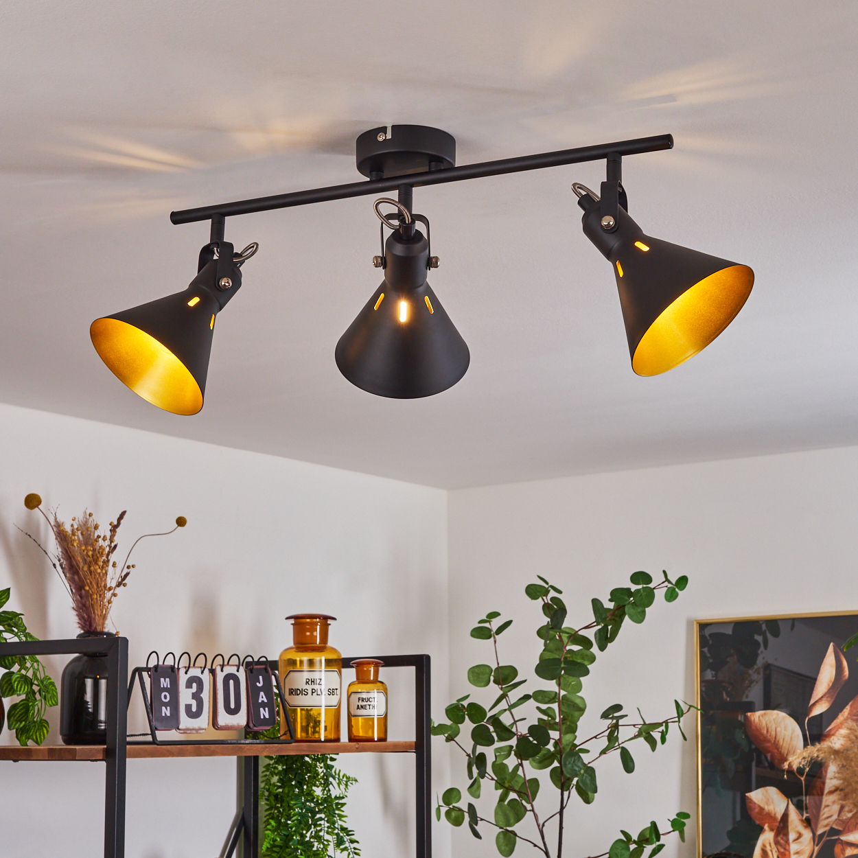 Schwarze Deckenleuchte mit drei verstellbaren Spots mit goldenen Innenseiten.