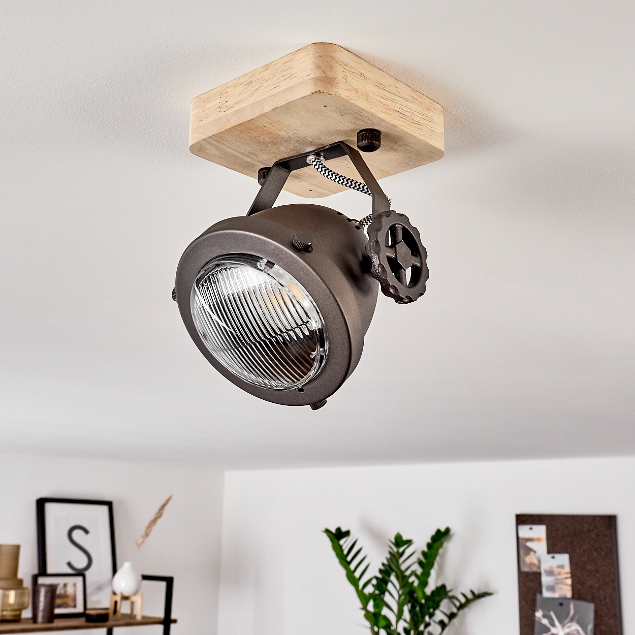 Eine rustikale Deckenleuchte mit Holzsockel und einem braunen Metallstrahler.