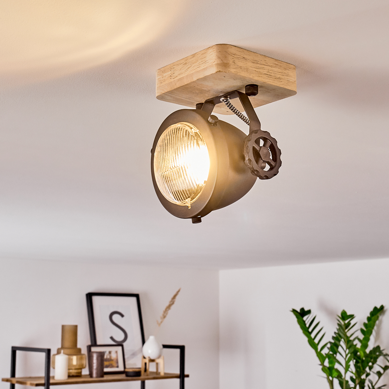 Eine Deckenleuchte mit Holzsockel und Metallstrahler im Industrie-Stil.