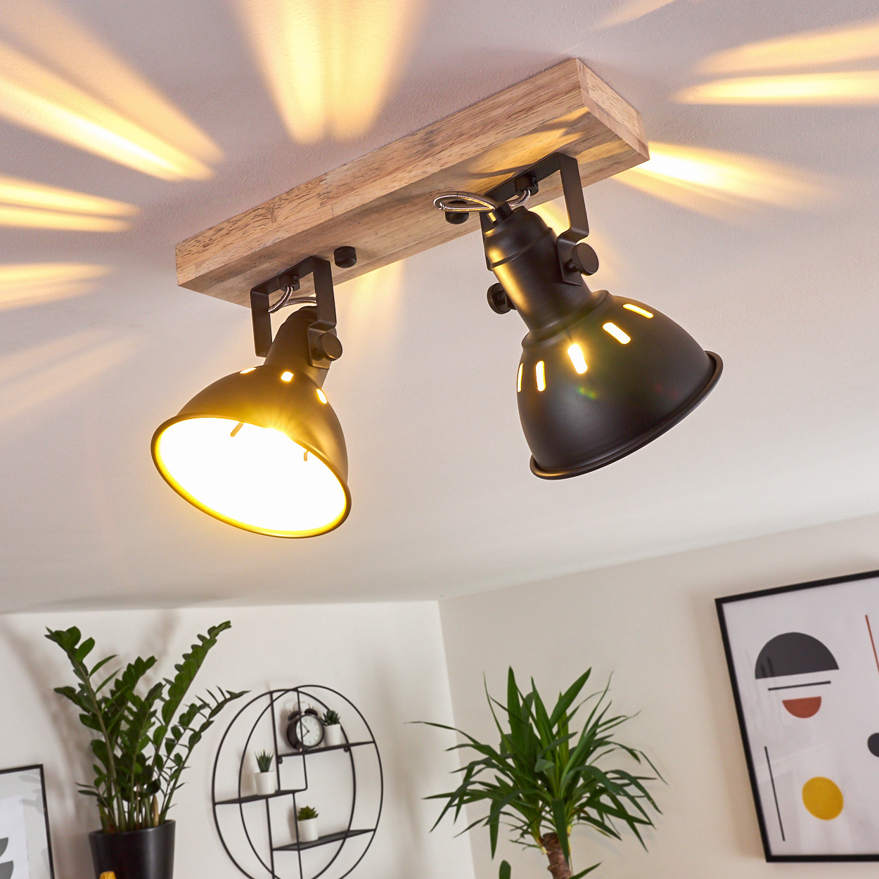 Zwei schwarze Lampenschirme hängen an einem Holzbalken, der Lichtstrahlen wirft.